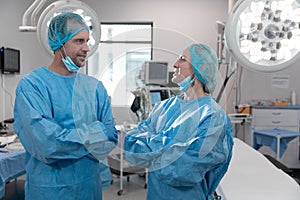 Portrait of caucasian male and female surgeons standing in operating theatre wearing face mask