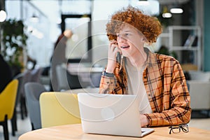 Portrait of Caucasian male freelancer in trendy apparel sitting at cafeteria table and doing remote work for programming