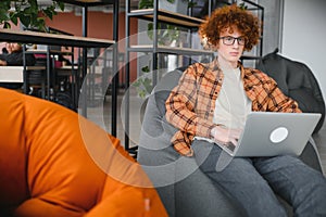 Portrait of Caucasian male freelancer in trendy apparel sitting at cafeteria table and doing remote work for programming