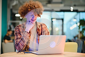 Portrait of Caucasian male freelancer in trendy apparel sitting at cafeteria table and doing remote work for programming