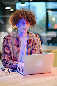 Portrait of Caucasian male freelancer in trendy apparel sitting at cafeteria table and doing remote work for programming