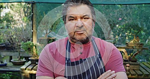 Portrait of Caucasian male gardener with crossed hands, looking at camera at garden center