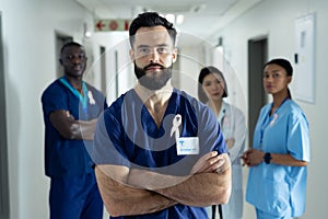 Portrait of caucasian male healthcare worker with cancer ribbon in busy hospital corridor