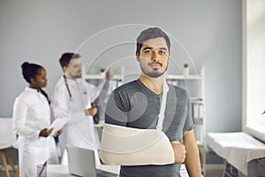 Portrait of caucasian man with bandage on broken hand standing in hospital ward