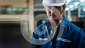 Portrait of caucasian man industrial worker or labor in blue factory uniform with white safty helmet in factory metal workshop