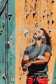 Portrait of Caucasian man professional rock climber standing at front of climbing wall at training center in sunny day