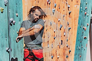 Portrait of Caucasian man professional rock climber standing at front of climbing wall at training center in sunny day