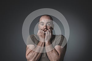 Portrait of caucasian man with scared expression bringing his hands to his face