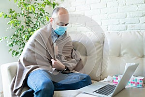 Man with covid19 and mask looking at laptop photo