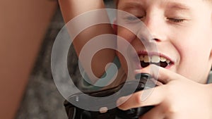 Portrait of a Caucasian preschooler boy cheerfully playing a game console. The child holds the joystick in his hands and the playe