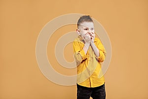 portrait of caucasian scared child boy on yellow background. amazed stressed boy in yellow shirt. school child afraid or