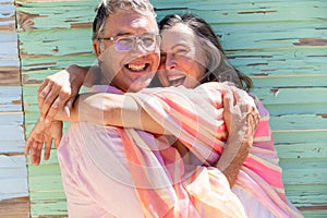 Portrait of caucasian senior couple embracing cheerfully while standing against wooden wall