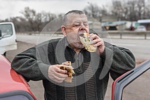 Portrait of Caucasian senior driver being delighted while gobbling lyulya kebab photo