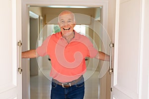 Portrait of caucasian senior man smiling while opening the front door of his house