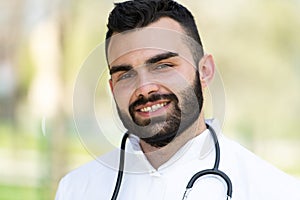 Portrait of a Caucasian smiling bearded Male Doctor with a stethoscope in the Park