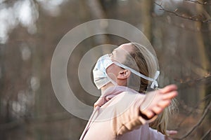 Portrait of caucasian sporty woman wearing medical protection face mask while relaxing by taking a deep breath in forest