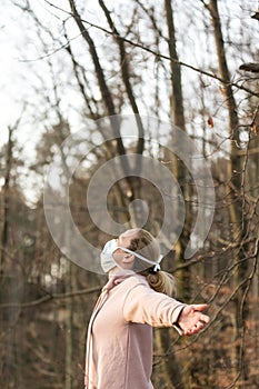 Portrait of caucasian sporty woman wearing medical protection face mask while relaxing by taking a deep breath in forest