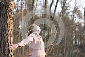 Portrait of caucasian sporty woman wearing medical protection face mask while relaxing by taking a deep breath in forest