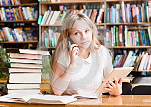 Portrait of a caucasian teen girl in library using tablet computer