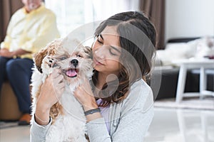 Portrait of Caucasian teenage girl playing with shih tzu puppy dog at home. Young beautiful woman sitting on floor, smiling,