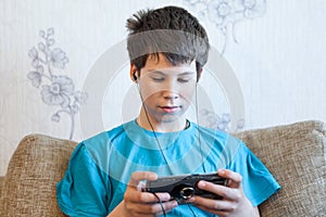 Portrait of Caucasian teenager with a large smartphone or game console in hands, playing or engaging over social media