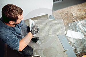 Portrait of caucasian tiler placing ceramic wall tile in position over adhesive with lash tile levelling system.