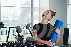 Portrait caucasian white woman smiling happily and holding a yoga mat and exercise ball