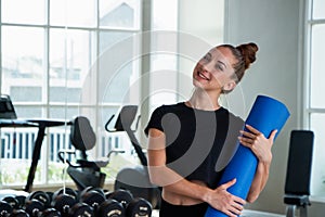 Portrait caucasian white woman smiling happily and holding a yoga mat and exercise ball