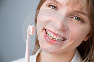 Portrait of a caucasian woman with braces on her teeth holding a toothbrush.