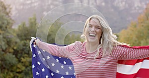 Portrait of caucasian woman holding flag of usa in garden, slow motion