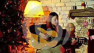 Portrait of Caucasian woman playing guitar and singing son in a New Year`s atmosphere