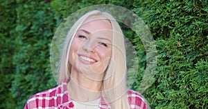 Portrait of caucasian woman posing near green hedge