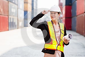 Portrait of Caucasian woman supervisor worker wearing hard hat work with tablet at a container yard. Shipping business management