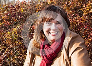 Portrait of a Caucasian Woman Wearing a Tan Leather Jacket and Red Scarf with a Fall Color Background