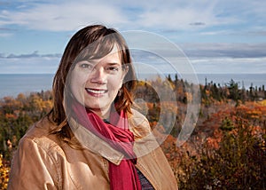 Portrait of a Caucasian Woman Wearing a Tan Leather Jacket and Red Scarf with a Scenic Fall Color and Ocean Background