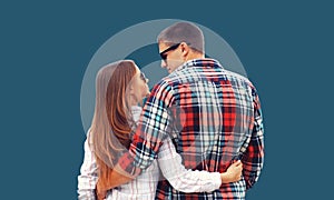 Portrait of caucasian young couple hugging and looking at each other on blue background