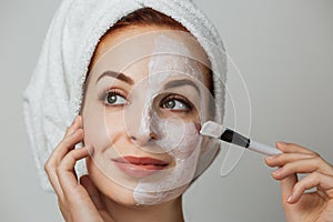 Portrait of caucasian young woman with using brush for applying facial skincare mask