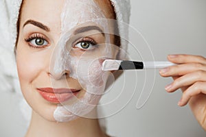 Portrait of caucasian young woman with using brush for applying facial skincare mask