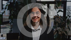 Portrait of a CEO girl in a jacket and glasses. Young businesswoman standing alone in the office