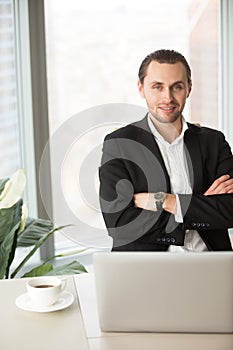 Portrait of CEO sitting at desk with arms crossed