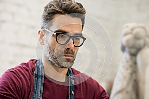 Portrait of Ceramist Dressed in an Apron Working on Clay Sculpture in Bright Ceramic Workshop.