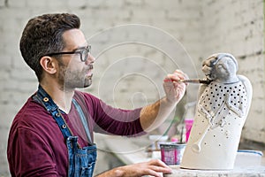 Portrait of Ceramist Dressed in an Apron Working on Clay Sculpture in Bright Ceramic Workshop.