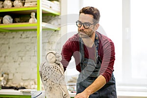 Portrait of Ceramist Dressed in an Apron Working on Clay Sculpture in Bright Ceramic Workshop.