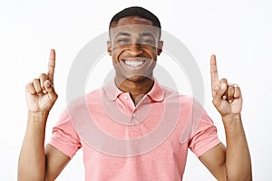 Portrait of charismatic good-looking pleasant and happy young african american guy lifting hands pointing up and smiling