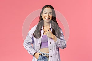 Portrait of charismatic pretty young woman in stylish streetstyle spring outfit, look camera, smiling and pointing left