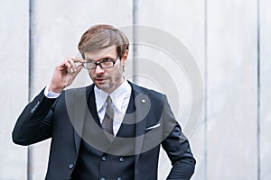 Portrait of charismatic young businessman in suit take off glasses