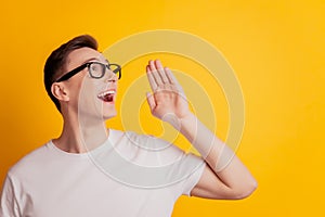 Portrait of charming announcer guy palm open mouth scream message blank space on yellow background