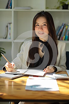 Portrait of a charming Asian businesswoman sitting at her office desk