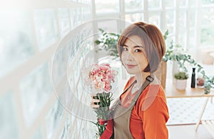 Portrait of charming Asian Korean Woman florist holding a bouquet flowers in hands