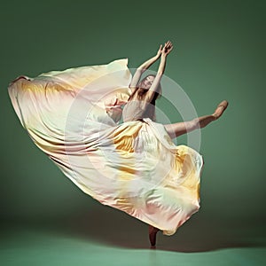 Portrait of charming ballerina, dancer wearing colorful dress over dark green background. Contemporary dance. Graceful